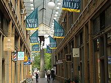 Atrium of a shopping arcade, with green and yellow banners hanging overhead with the words